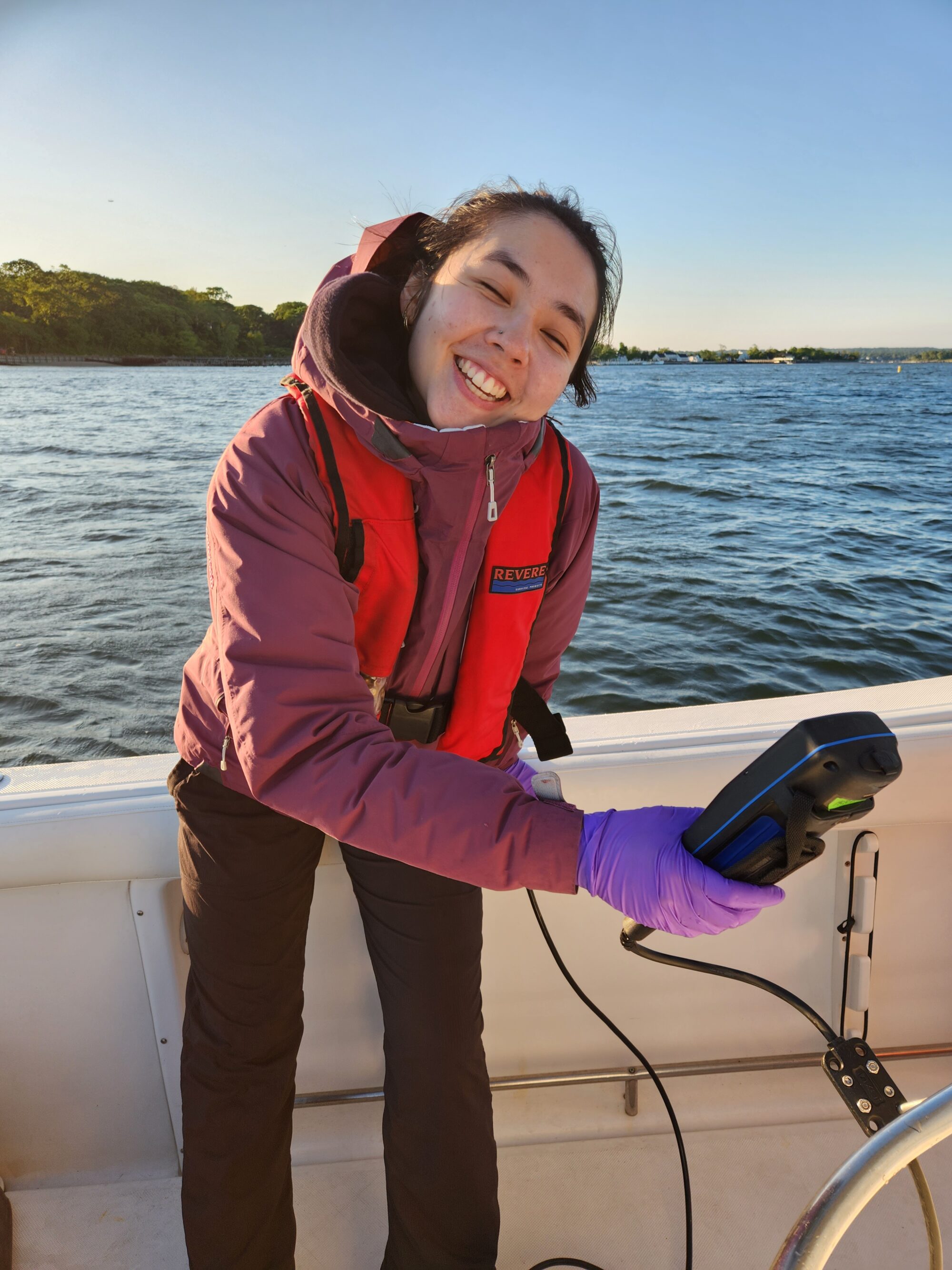 Kyra Lin smiles, holding a testing device for water quality. 