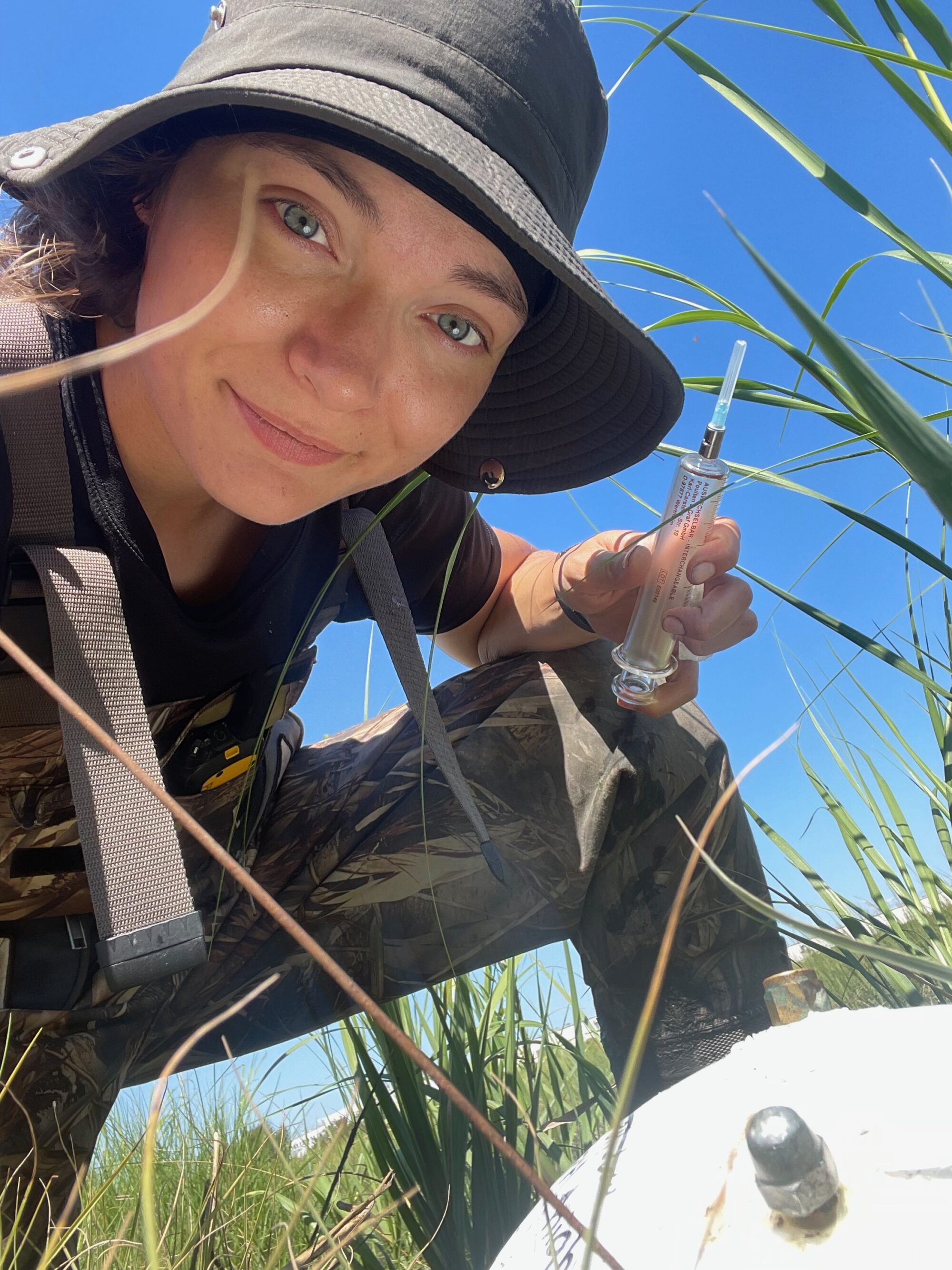 Madeline Kollegger crouches and takes a selfie in the field. 