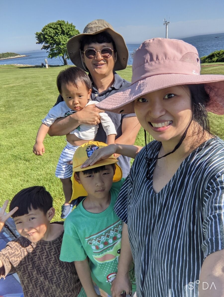 An asian man and woman pose with their three children at the park. 